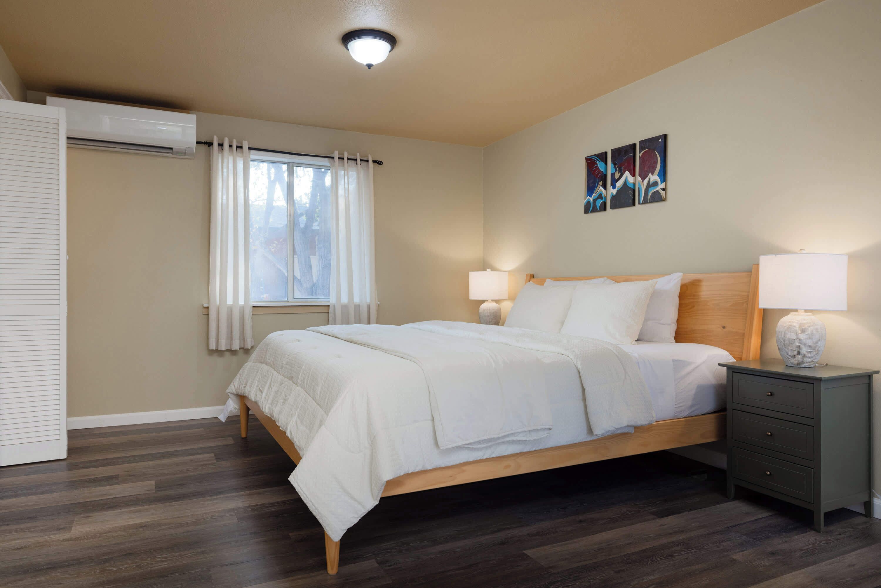Une chambre à coucher avec un lit, des lampes de chevet, une table de chevet et une fenêtre avec des rideaux.
