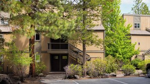 A building with a covered entrance, a parking area, and surrounding greenery. - Bend Condo Near Mt Bachelor with Hot Tub Sleeps 6 (Bend)