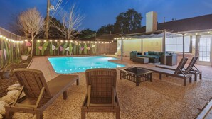 A backyard with a swimming pool, outdoor furniture, and string lights. - Sageview Cottage – 4 BDR w/ Pool, Pet Friendly! (Houston)