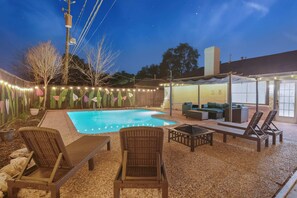 A backyard with a swimming pool, wicker lounge chairs, and a covered seating area with cushions. - Sageview Cottage – 4 BDR w/ Pool, Pet Friendly! (Houston)