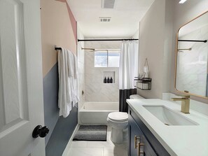 A modern bathroom with a bathtub, toilet, and vanity.