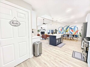 A modern kitchen with a central island, stainless steel appliances, and a dining area with a colorful abstract wall art.