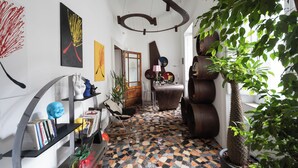 A modern interior with a mosaic floor, a large potted tree, and abstract wall art. - Palazzo il Convento (Naples)