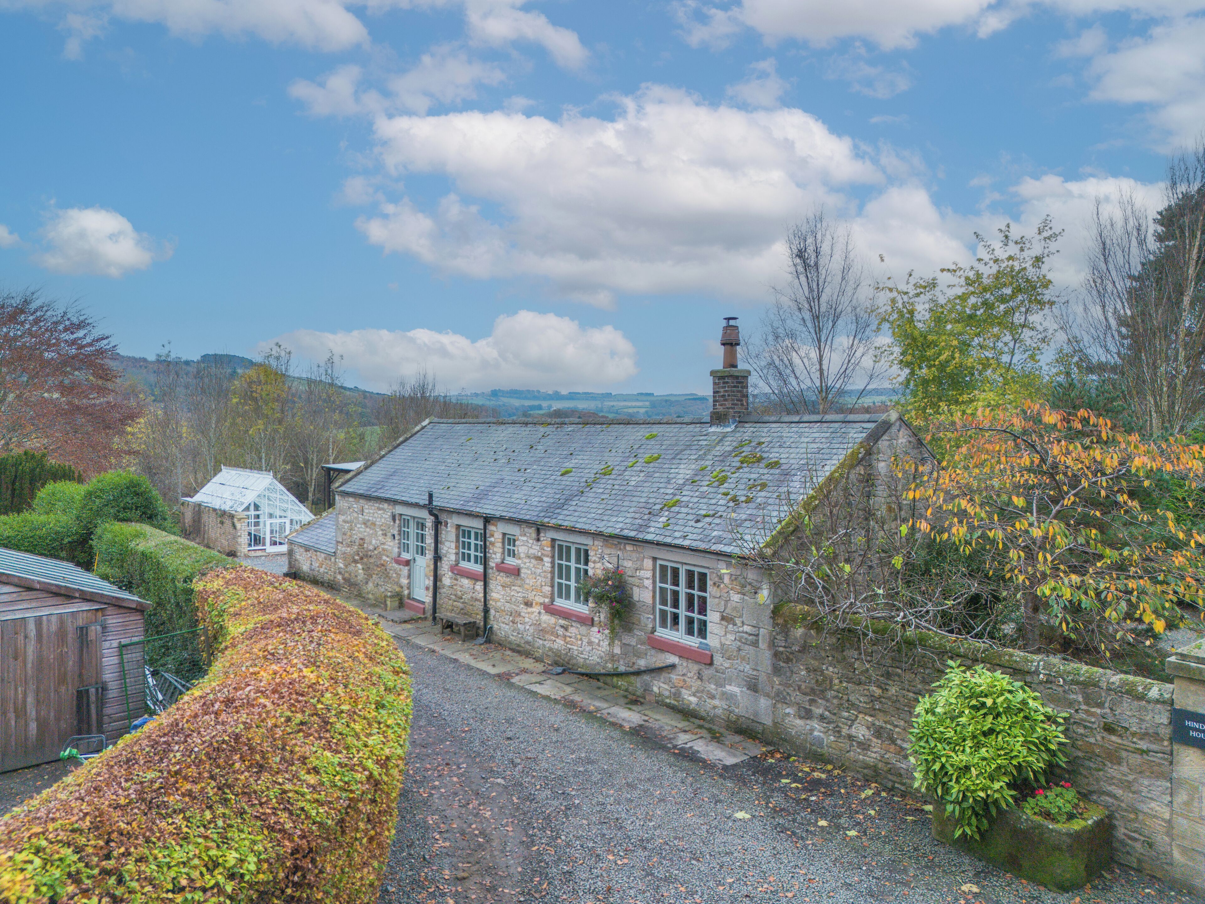 A stone building with a sloped roof, a chimney, and a small window.