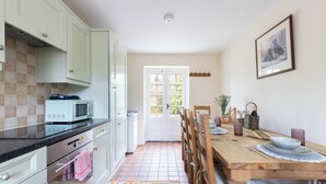 A kitchen with white cabinets, a microwave, and a tiled floor. - Keeper's Cottage - North East Escapes  (Stocksfield)