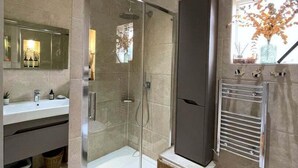 A modern bathroom with a glass-enclosed shower, a vanity with a mirror, and a toilet.