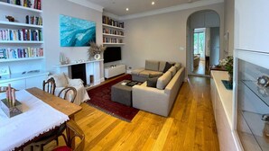 A modern living room with a fireplace, bookshelves, a sofa, and a dining area.