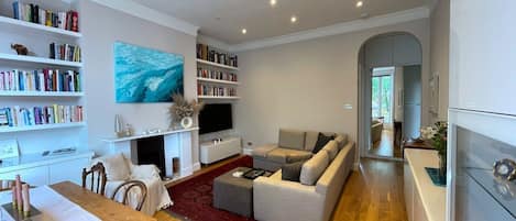 A modern living room with a fireplace, bookshelves, a sofa, and a dining area.