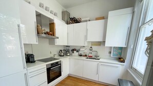 A modern kitchen with white cabinetry, a wooden floor, and a built-in oven.