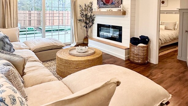 A spacious living room with a large sofa, a fireplace, and a ceiling fan. - Charming Cape Cod Getaway- EV Charger, Mini Golf, Walk to The Beach, Pets Okay! (Yarmouth)