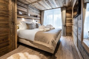 A wooden cabin bedroom with a bed, pillows, and a blanket.