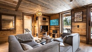 A cozy log cabin interior with a fireplace, comfortable seating, and a television mounted on the wall. - Wifi, 150m from ski slopes, Ground floor, sauna, hammam, terrace, fireplace or stove, tv, 120m² (Méribel - Les Allues)