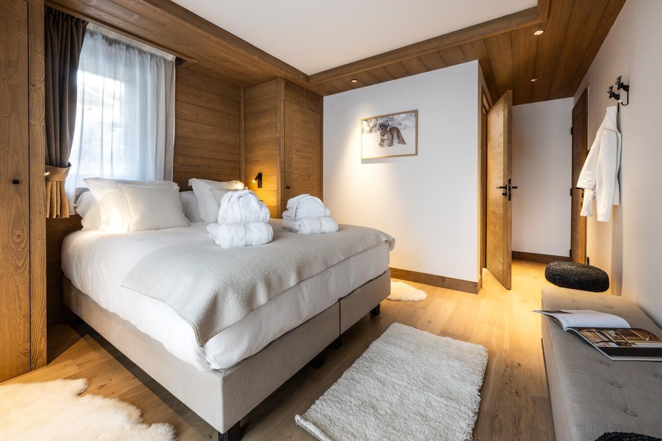 Ett modernt sovrum med en stor säng, träpanel på väggarna, en vit matta och en ombonad atmosfär.