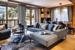 Un salon moderne avec un grand canapé d’angle, une table basse ronde et une cheminée.