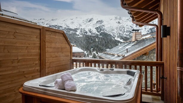 A wooden cabin with a hot tub on a balcony overlooking a snowy mountain landscape. - Wifi, 150m from ski slopes, view mountain, sauna, hammam, terrace, balcony, tv, 78m², Méribel (Méribel - Les Allues)