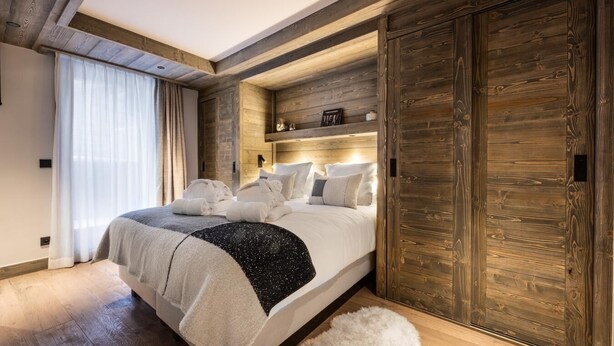 Ein modernes Schlafzimmer mit einem großen Bett, Holzvertäfelung und einem flauschigen Teppich.
