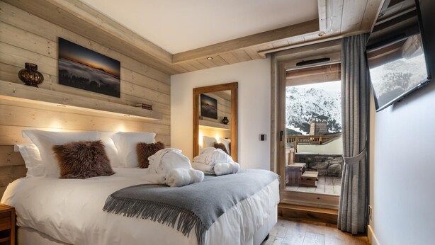 A bedroom with a large bed, wooden walls, and a view of the outdoors. - Wifi, 150m from ski slopes, 1st floor, view mountain, sauna, hammam, terrace, balcony (Méribel - Les Allues)
