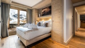 A spacious bedroom with a large bed, wooden walls, and a view of a snowy landscape. - Wifi, 150m from ski slopes, 1st floor, view mountain, sauna, hammam, terrace, balcony (Méribel - Les Allues)