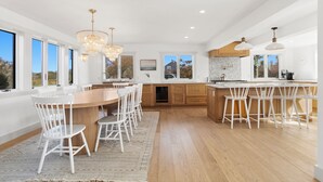 A spacious kitchen with a large island, white bar stools, and a view of the outdoors. - West of Town, a quiet corner of luxury  (Nantucket)