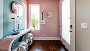 A room with a pink wall, a white guitar, a disco ball, and a mirror with a neon sign. - Pink Palace ⁞ DT views ⁞ 5min 2 Broadway (Nashville)