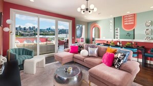 A modern living room with a pink sofa, a round coffee table, and a city view through large sliding doors. - Pink Palace ⁞ DT views ⁞ 5min 2 Broadway (Nashville)