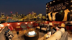 A rooftop bar with a city skyline view, a fire pit, and a mural of cowgirls. - Pink Palace ⁞ DT views ⁞ 5min 2 Broadway (Nashville)