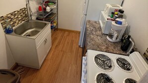 A compact kitchen with a sink, stove, and refrigerator. - Quaint Rural Cabin Near Hatcher Pass (Wasilla)