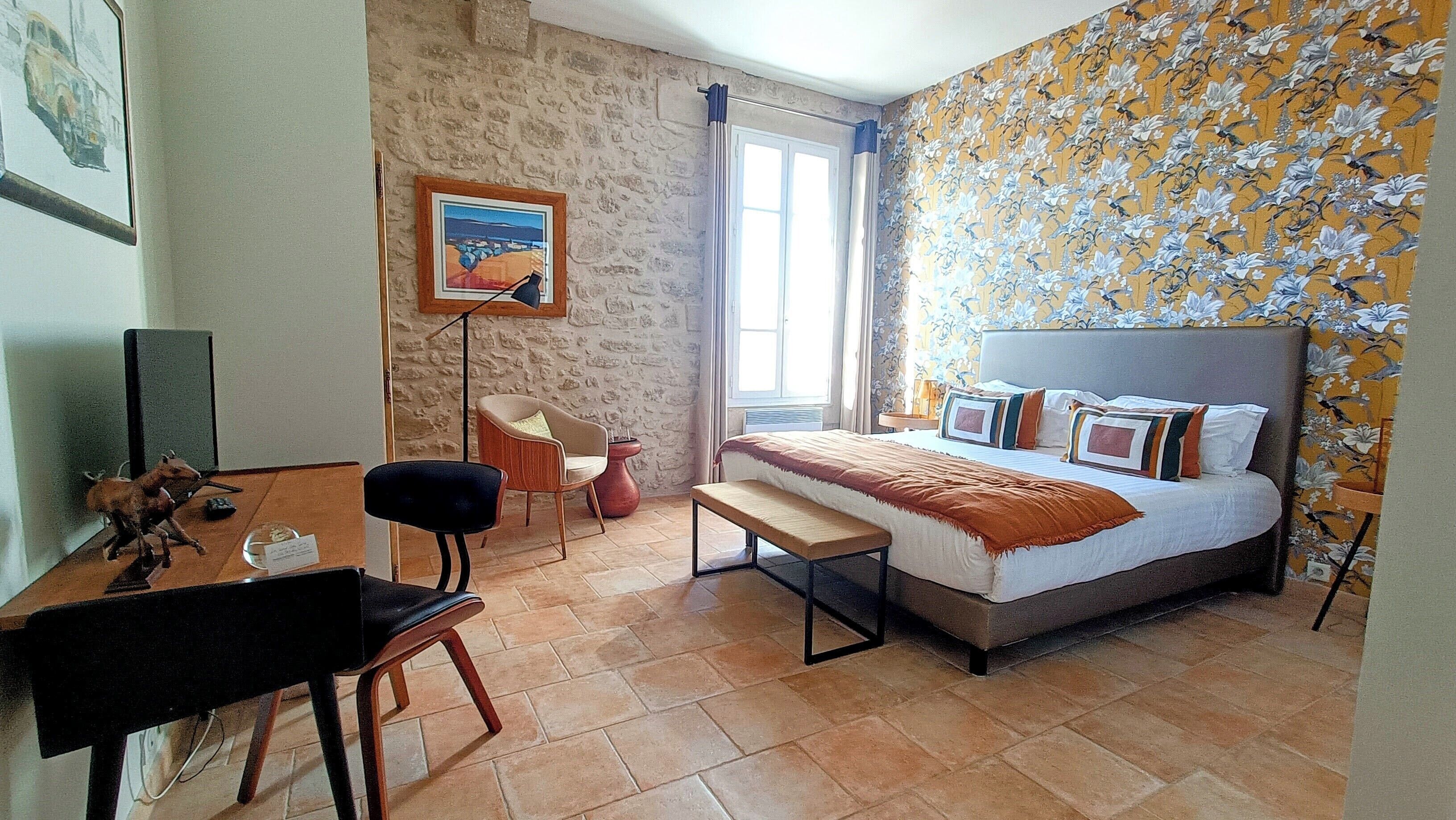 A bedroom with a bed, a desk, a chair, and a painting on the wall.