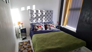 A bedroom with a tufted headboard, a bed with a green blanket, a patterned rug, and a window with curtains. - Charming Ab25 Free Parking (Aberdeen)