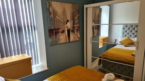 A hotel room with a bed, a window with blinds, a painting on the wall, and a mirror reflecting the room. - Charming Ab25 Free Parking (Aberdeen)
