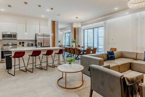 Una cocina moderna con electrodomésticos de acero inoxidable, un comedor con sillas rojas y un amplio ventanal que proporciona luz natural.