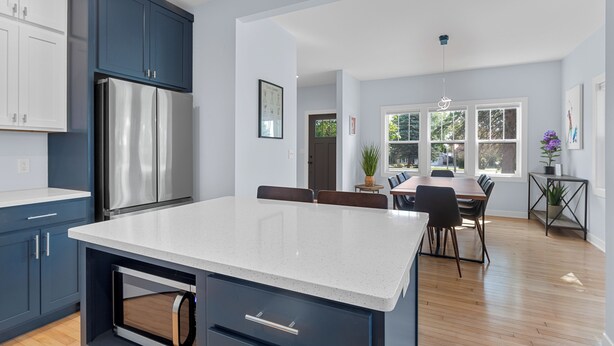 Una cocina moderna con una isla grande, armarios azul oscuro y un refrigerador de acero inoxidable.