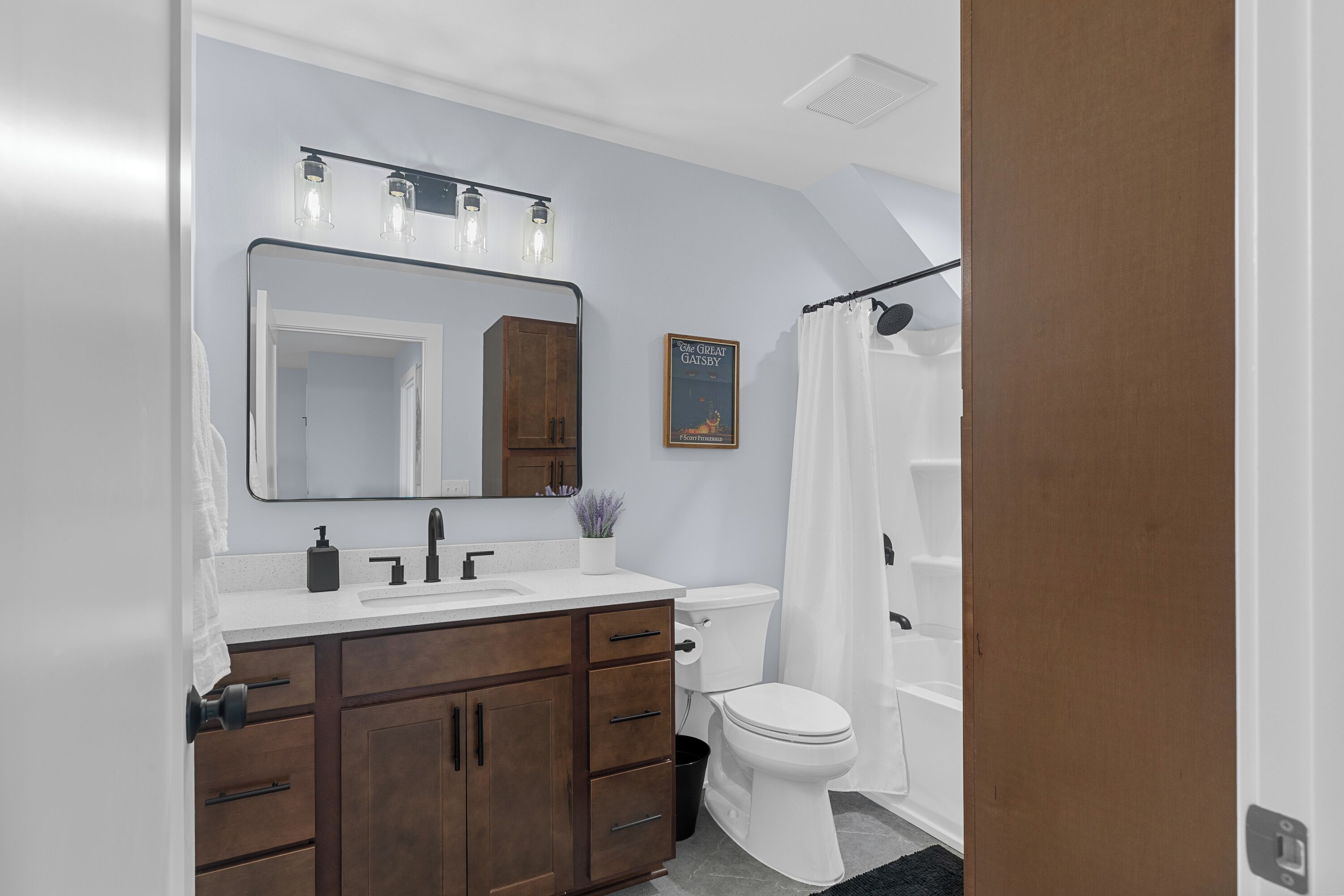 Ein Badezimmer mit Waschbecken, dunklem Holzschrank, Toilette und Duschvorhang.