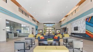 Eine geräumige Lobby mit einer zentralen Sitzecke, Glaswänden und einem modernen, geometrischen Wanddesign.