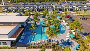 Ein moderner Wohnkomplex mit einem zentralen Schwimmbecken, umgeben von Liegestühlen und Palmen.