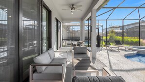 A modern outdoor lounge area with a pool, seating, and large windows.