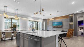 A modern kitchen with a large island, dining area with chairs, and a view of the outdoors.