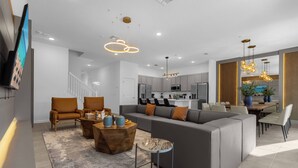 A modern living room with a sectional sofa, a coffee table, and a TV mounted on the wall.