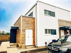 A modern two-story house with a garage, a driveway, and a parked car.