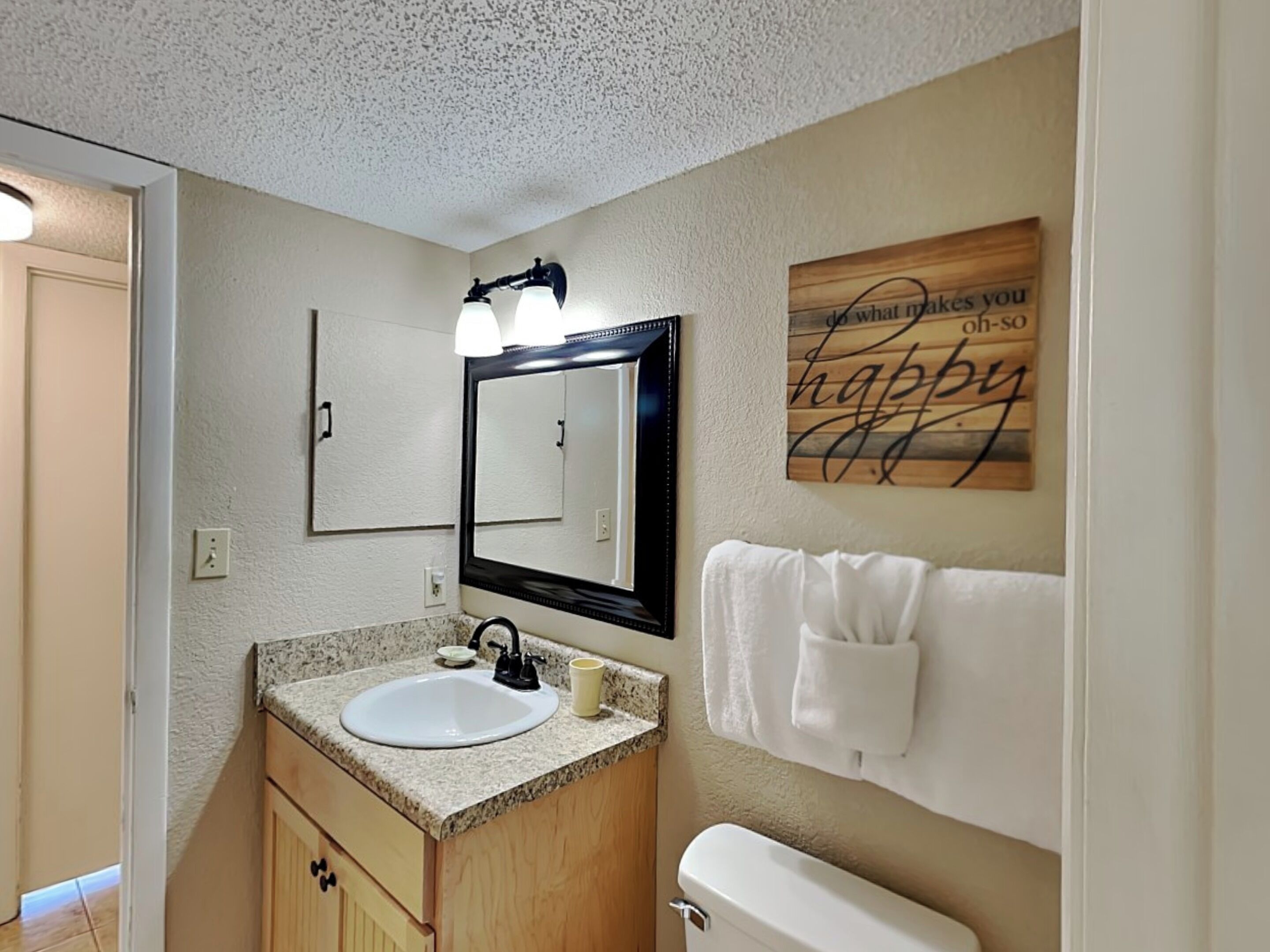 A bathroom with a sink, mirror, and towel rack.