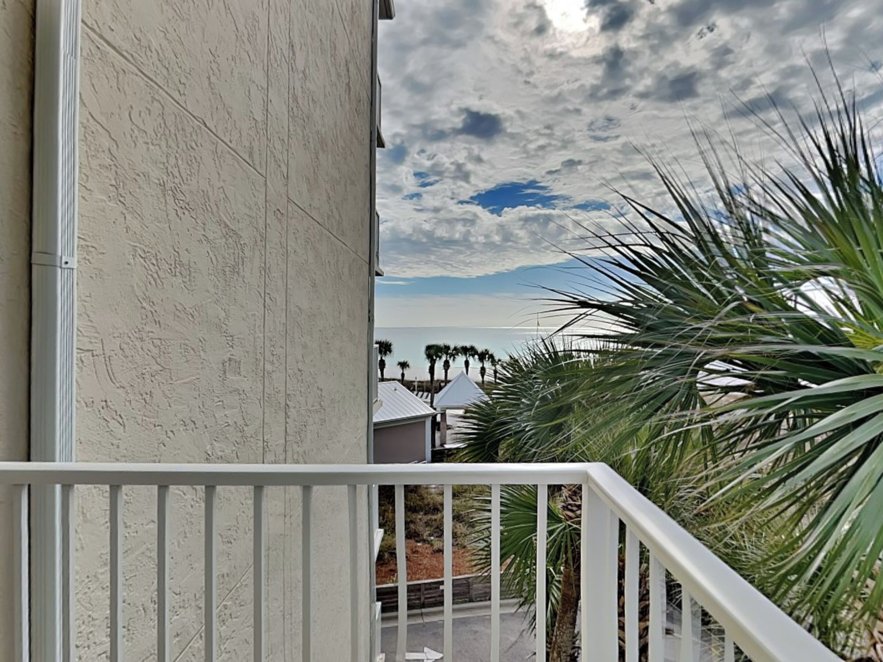 A balcony with a view of the ocean and palm trees.