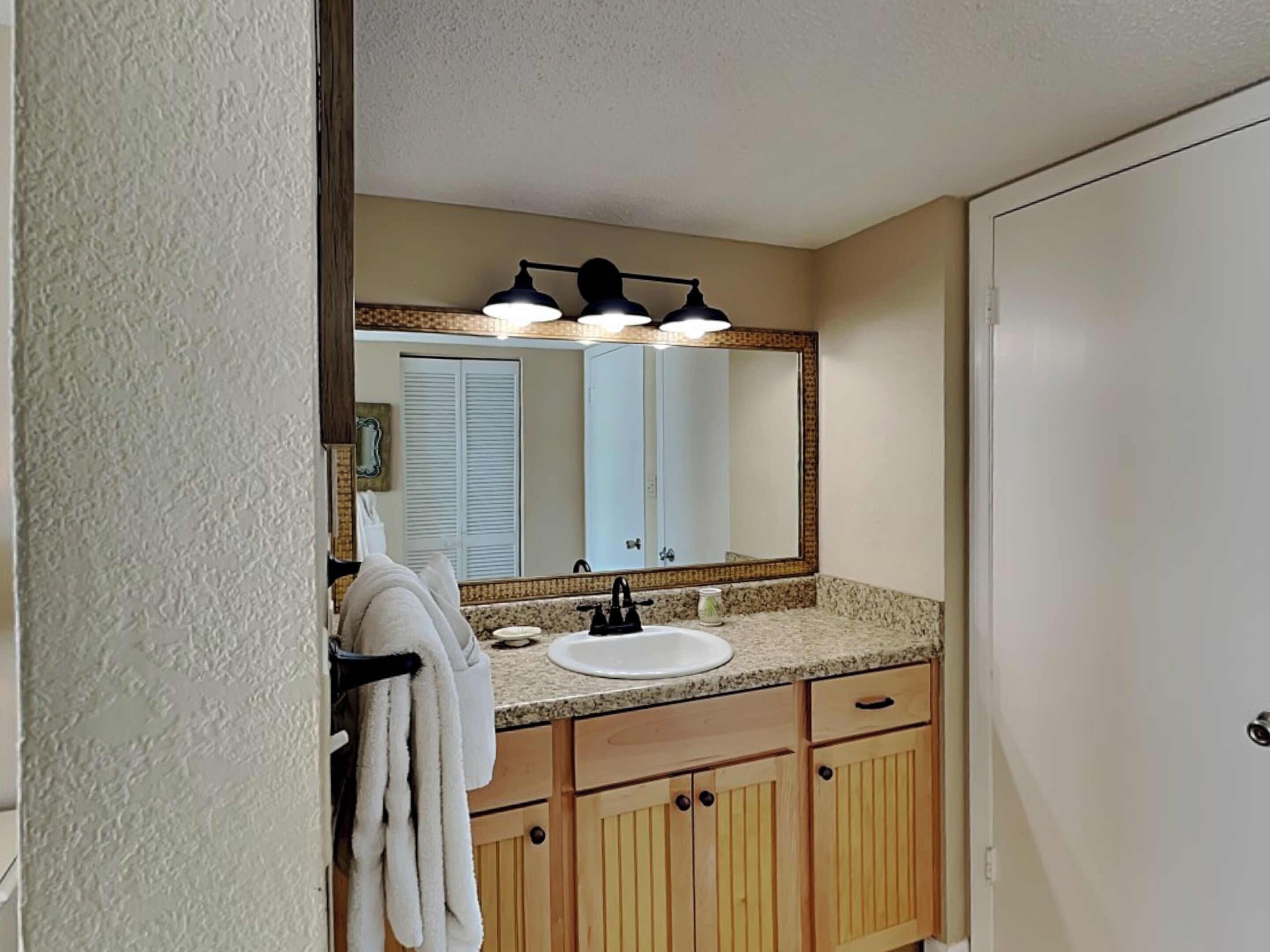 A bathroom with a sink, mirror, towel rack, and wooden cabinets.