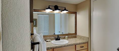 A bathroom with a sink, mirror, towel rack, and wooden cabinets.