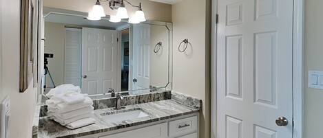 A bathroom with a white vanity, a large mirror, and a triple light fixture above the sink.