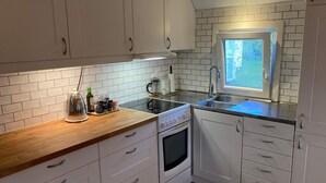 A compact kitchen with white cabinets, a wooden countertop, a built-in oven, and a window with a decorative view. - 5 Person Holiday Home in Falkenberg (Falkenberg)
