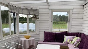 A cozy porch with a cushioned bench, a small table, and a chair. - 5 Person Holiday Home in Falkenberg (Falkenberg)