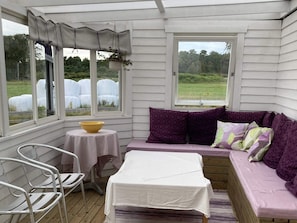 A covered porch with a cushioned seating area, a small table, and a chair. - 5 Person Holiday Home in Falkenberg (Falkenberg)