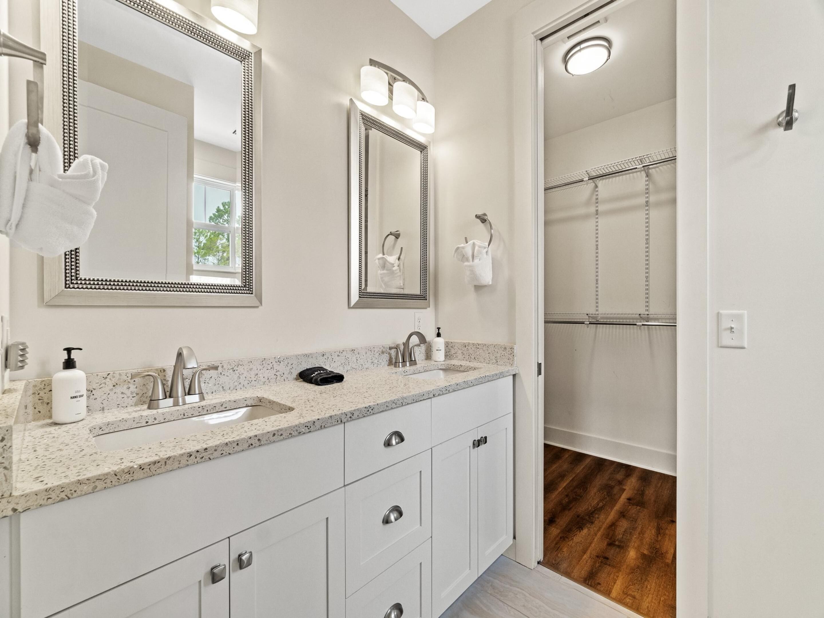Une salle de bain moderne avec un comptoir en granit, deux vasques et une douche à l’italienne.