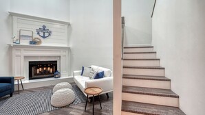 A living room with a fireplace, a white sofa, and a staircase. - 2 Primary Suites | FREE Pool Heat | Great Beaches (Sarasota)
