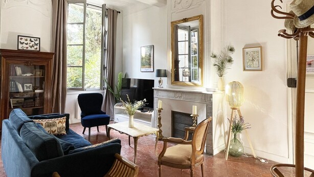 Een goed verlichte woonkamer met een open haard, een blauwe bank, een houten stoel en een televisie.
